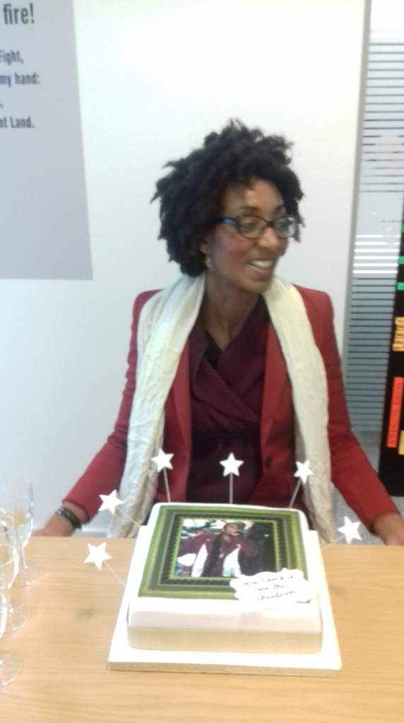 [decorative image] Photo of MG Zimeta seated at a table with a cake in front of her. She is facing sideways and laughing with someone off-camera The cake has a large picture on it of the rapper ODB from the Wu Tang Clan.   The picture is from the 1998 Grammys when ODB rushed the stage to express regret that Wu Tang had not won the Best Album award, because he had bought this nice suit to celebrate the win, and where he coined the phrase "Wu Tang is for the children" (which is also on the side of the cake as a label made of icing).  MG Zimeta is wearing the same outfit as ODB.